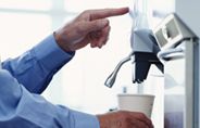 Man at vending machine taking a cup of coffee